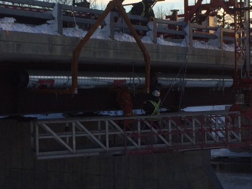 Installation de conduites pré isolées avec revêtement galvanisé sous un pont.